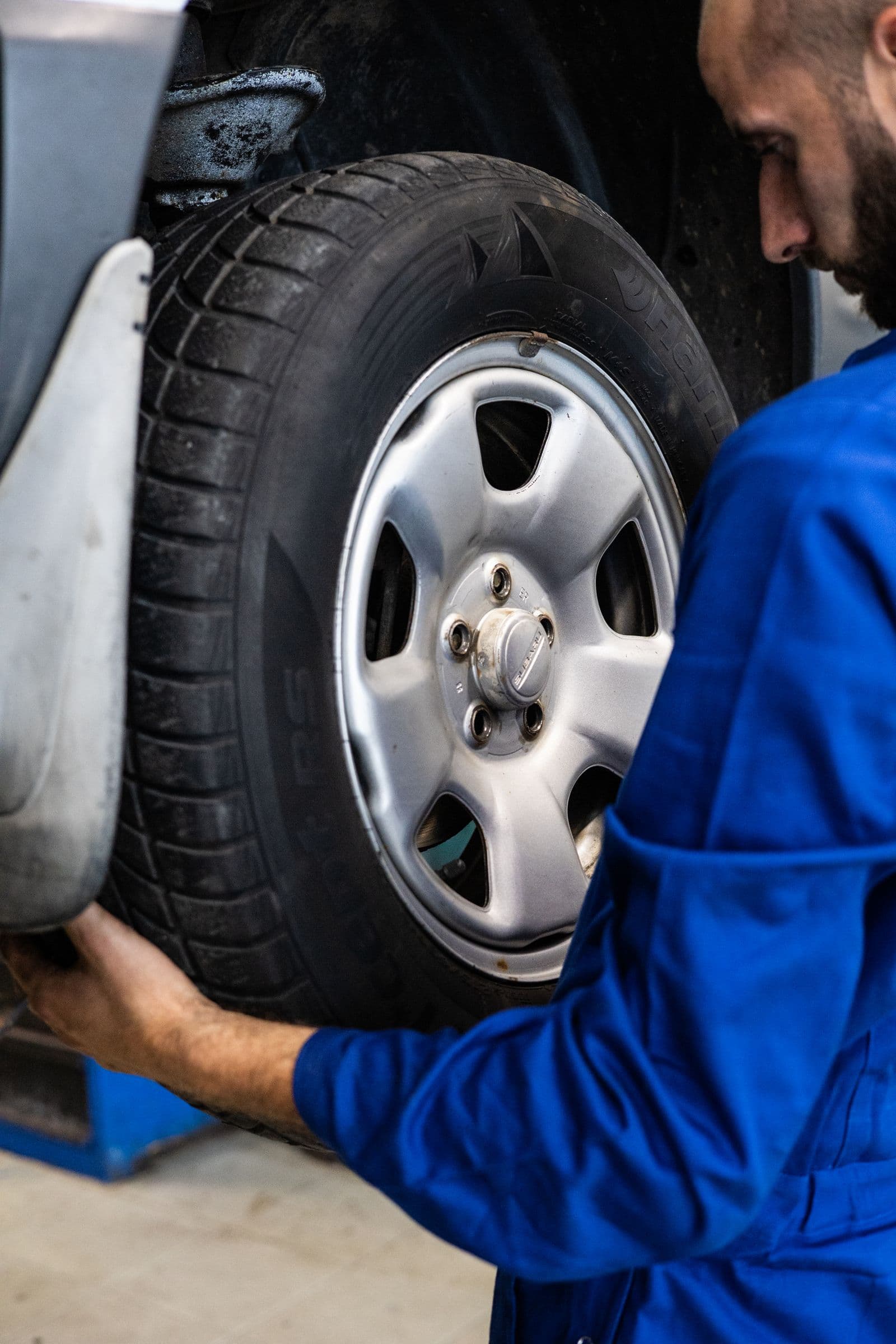 Technicien inspectant un pneu monté sur une voiture en atelier